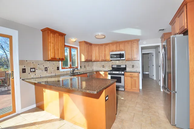a kitchen with stainless steel appliances granite countertop a sink a stove and a refrigerator