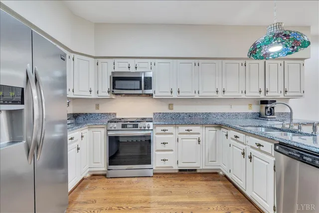 a kitchen with stainless steel appliances granite countertop a stove top oven a refrigerator and a sink