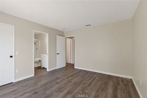 a view of an empty room with wooden floor and closet