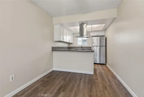 a kitchen with wooden floor white cabinets and stainless steel appliances