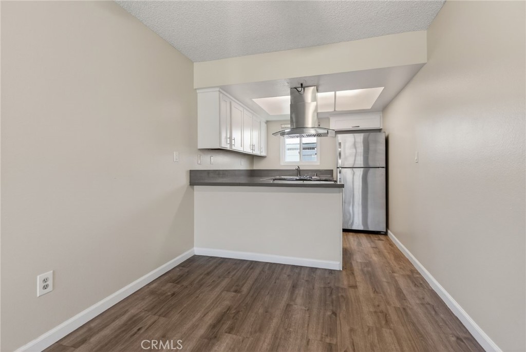 2891 Canyon Crest, Unit 32 Riverside, CA 92507 - Photo 8 of 27 a kitchen with wooden floor white cabinets and stainless steel appliances