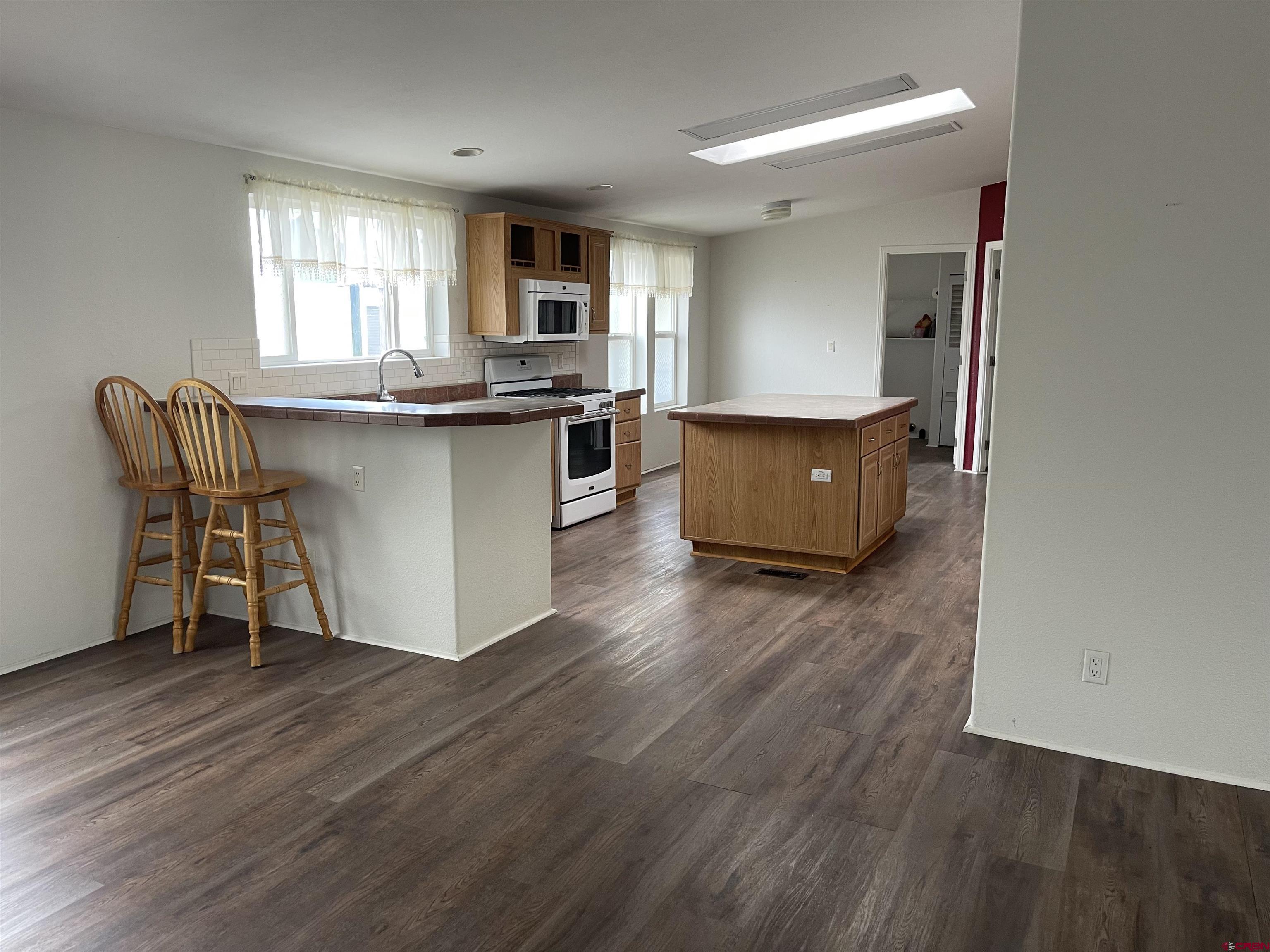 28260 Highway 160, Unit 1 Cortez, CO 81321 - Photo 7 of 21 a living room with kitchen island granite countertop wooden floor and a window