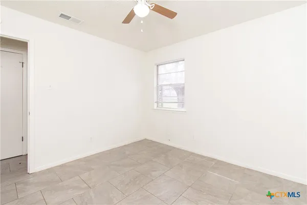an empty room with a ceiling fan and a window
