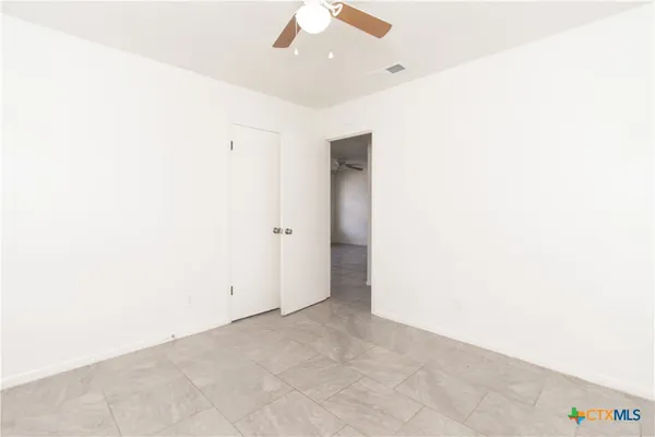 an empty room with a ceiling fan and a window
