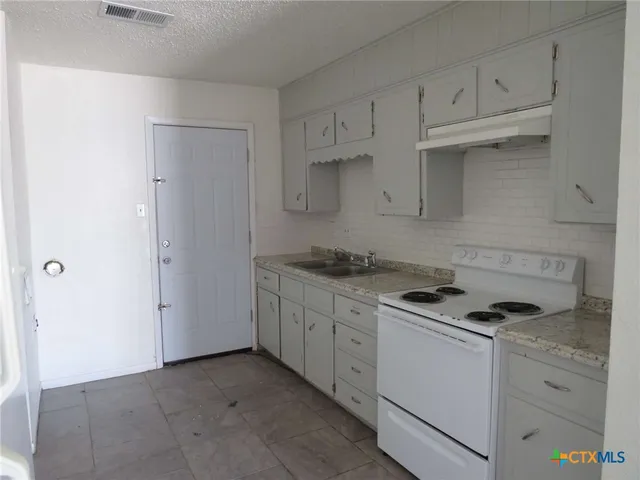 a kitchen with granite countertop cabinets and white appliances