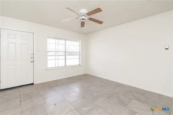 an empty room with a ceiling fan and a window