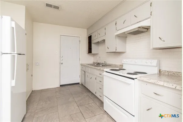 a kitchen with granite countertop white cabinets and white appliances