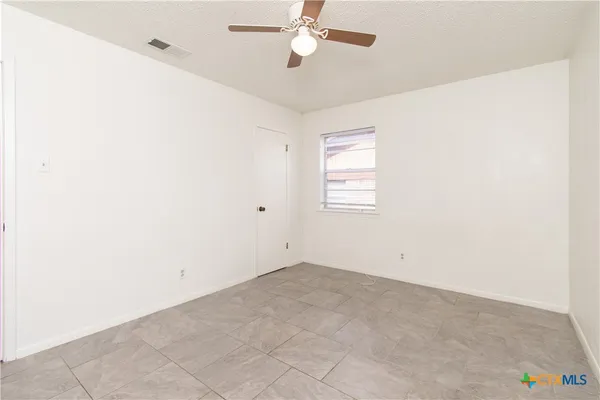 an empty room with a window and a ceiling fan