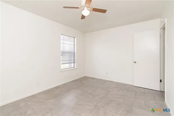 an empty room with windows and fan