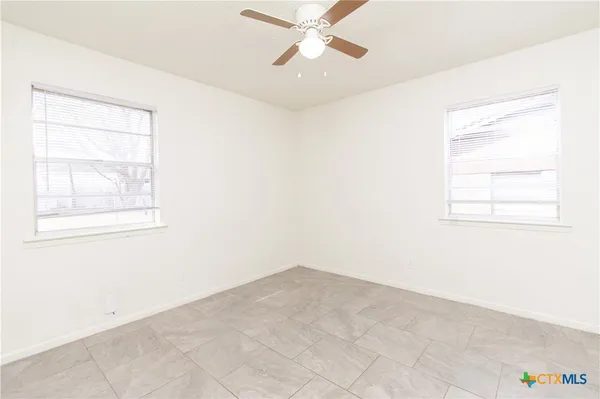 an empty room with a window and a fan