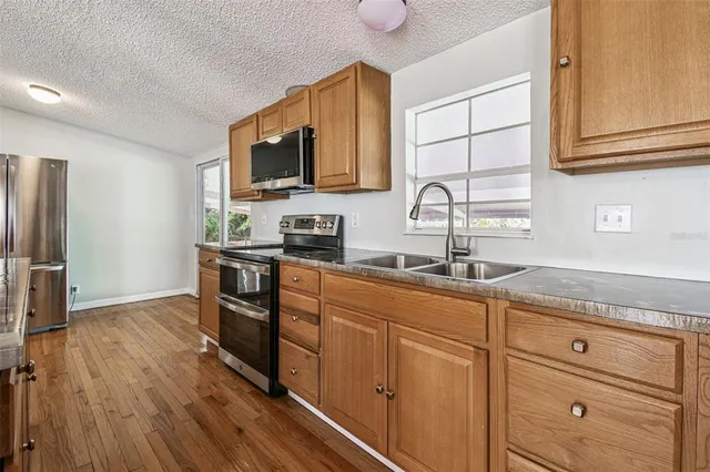 a kitchen with granite countertop a sink cabinets stainless steel appliances and wooden floor