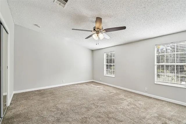 an empty room with windows and fan