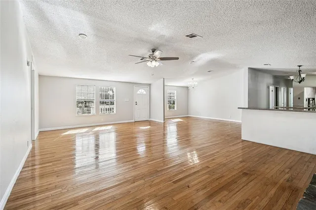 a view of an empty room with window and wooden floor