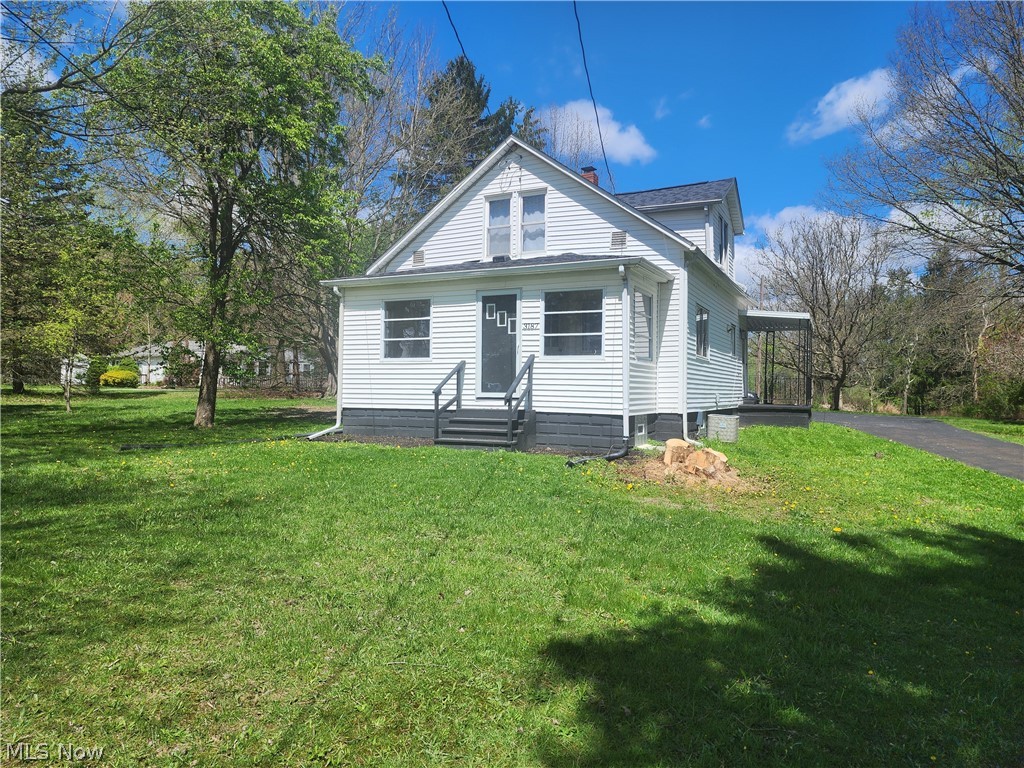 3187 Grenfall Road Barberton, OH 44203 - Photo 2 of 17 White siding residence with a dark-trimmed foundation, a covered side porch, and a paved driveway