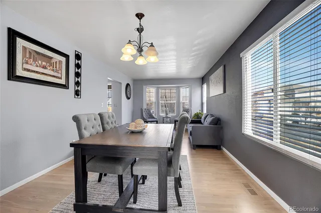 a kitchen with stainless steel appliances granite countertop a stove top oven a sink dishwasher a dining table and chairs with wooden floor