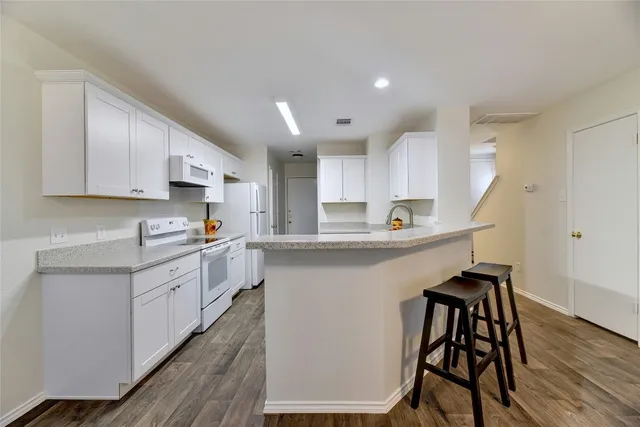 a kitchen that has a lot of cabinets a sink and wooden floor