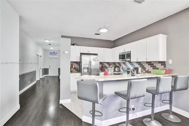 a kitchen with stainless steel appliances a dining table chairs microwave and cabinets