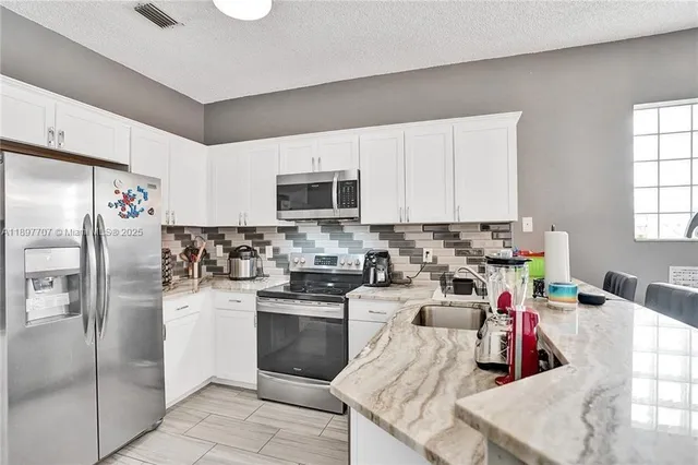 a kitchen with stainless steel appliances granite countertop a refrigerator sink and stove