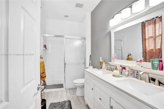 a bathroom with a double vanity sink toilet and shower