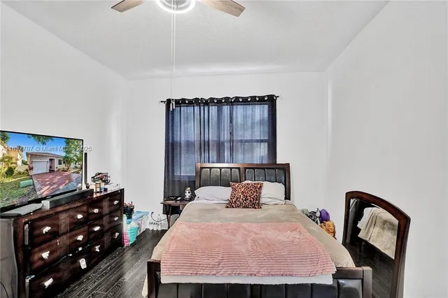 a bedroom with a bed a mirror on dresser and a window