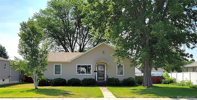 a front view of a house with a yard and trees