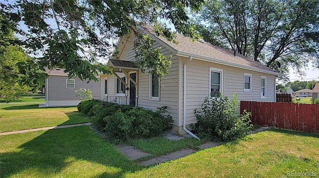 a view of a house with a big yard plants and large trees