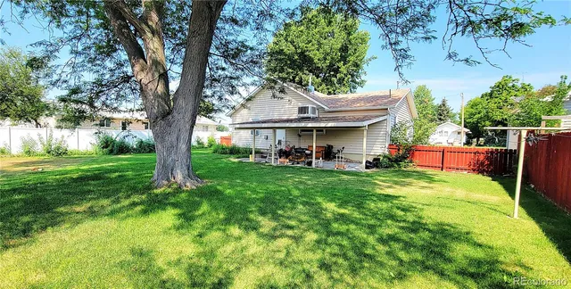 a view of a house with a yard deck and a large tree