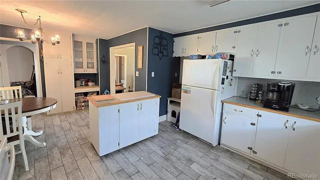 a kitchen with granite countertop a refrigerator a stove a sink a dining table and chairs with wooden floor