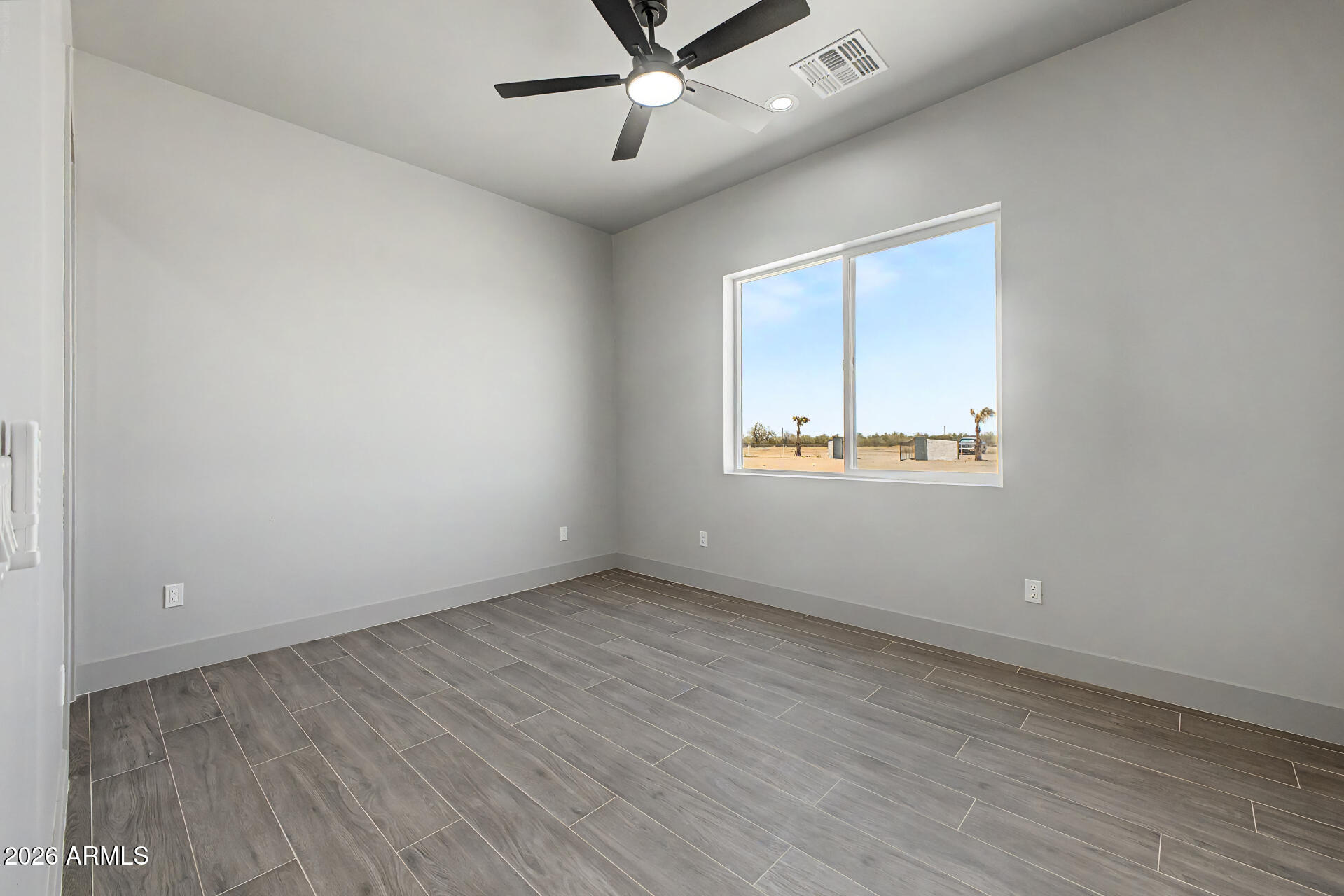 40461 West Robles Road Stanfield, AZ 85172 - Photo 39 of 54 an empty room with wooden floor ceiling fan and windows