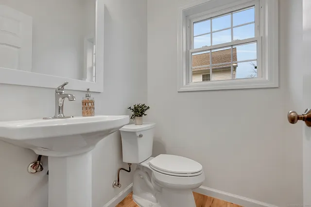 a bathroom with a sink mirror toilet and next to a window