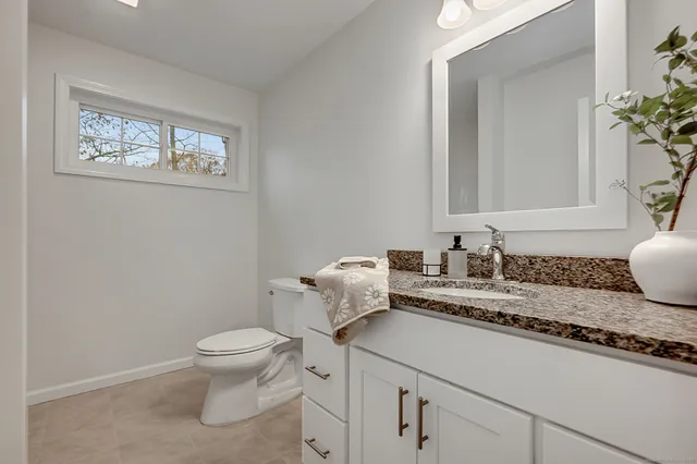a bathroom with a granite countertop toilet sink and mirror