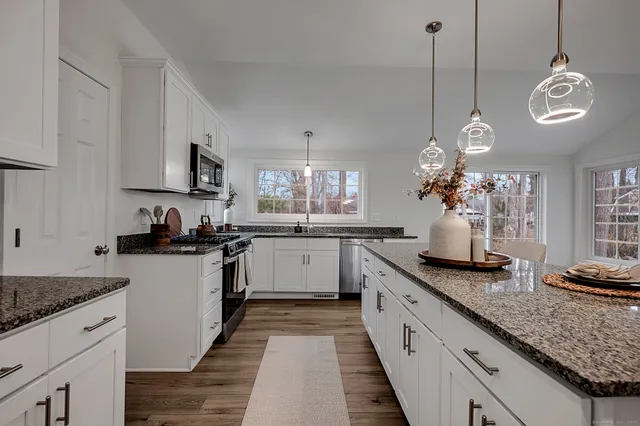 a large kitchen with kitchen island granite countertop a sink a stove and a wooden floors