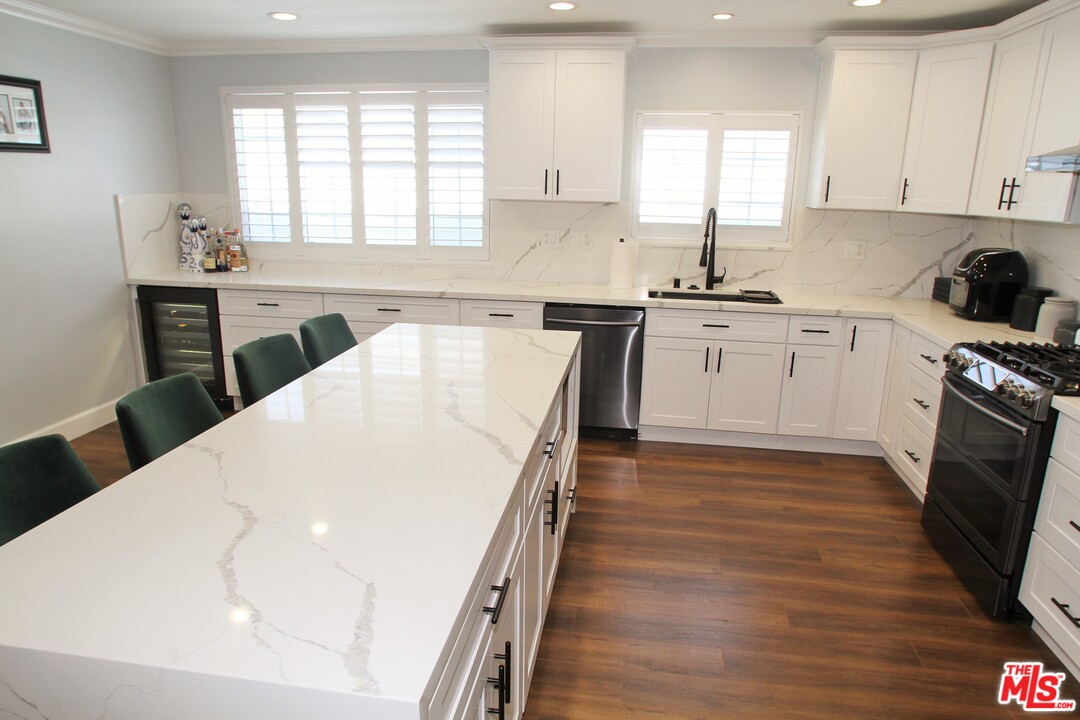 1712 West Poplar Street Compton, CA 90220 - Photo 13 of 41 a kitchen with granite countertop white cabinets a sink a window and appliances