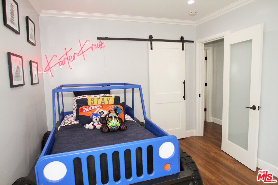 1712 West Poplar Street Compton, CA 90220 - Photo 19 of 41 a bedroom with a bed and a table with wooden floor