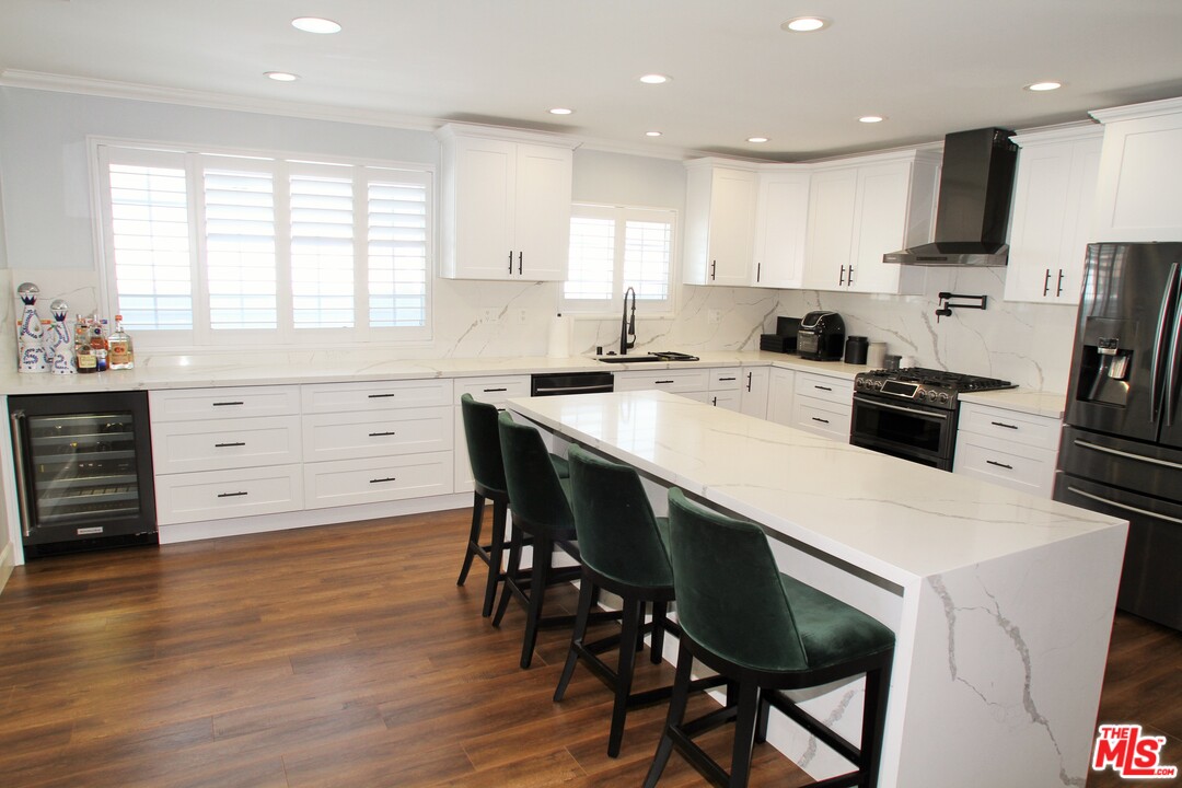 1712 West Poplar Street Compton, CA 90220 - Photo 10 of 41 a kitchen with a table a refrigerator a cabinets and stools