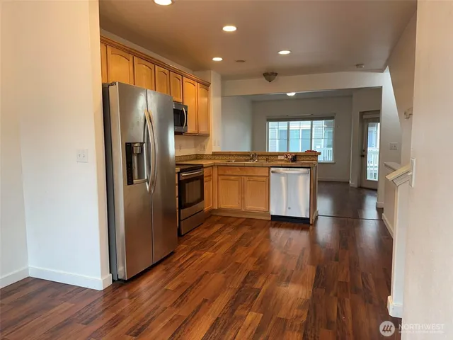 a kitchen with stainless steel appliances granite countertop a refrigerator a stove top oven a sink and dishwasher