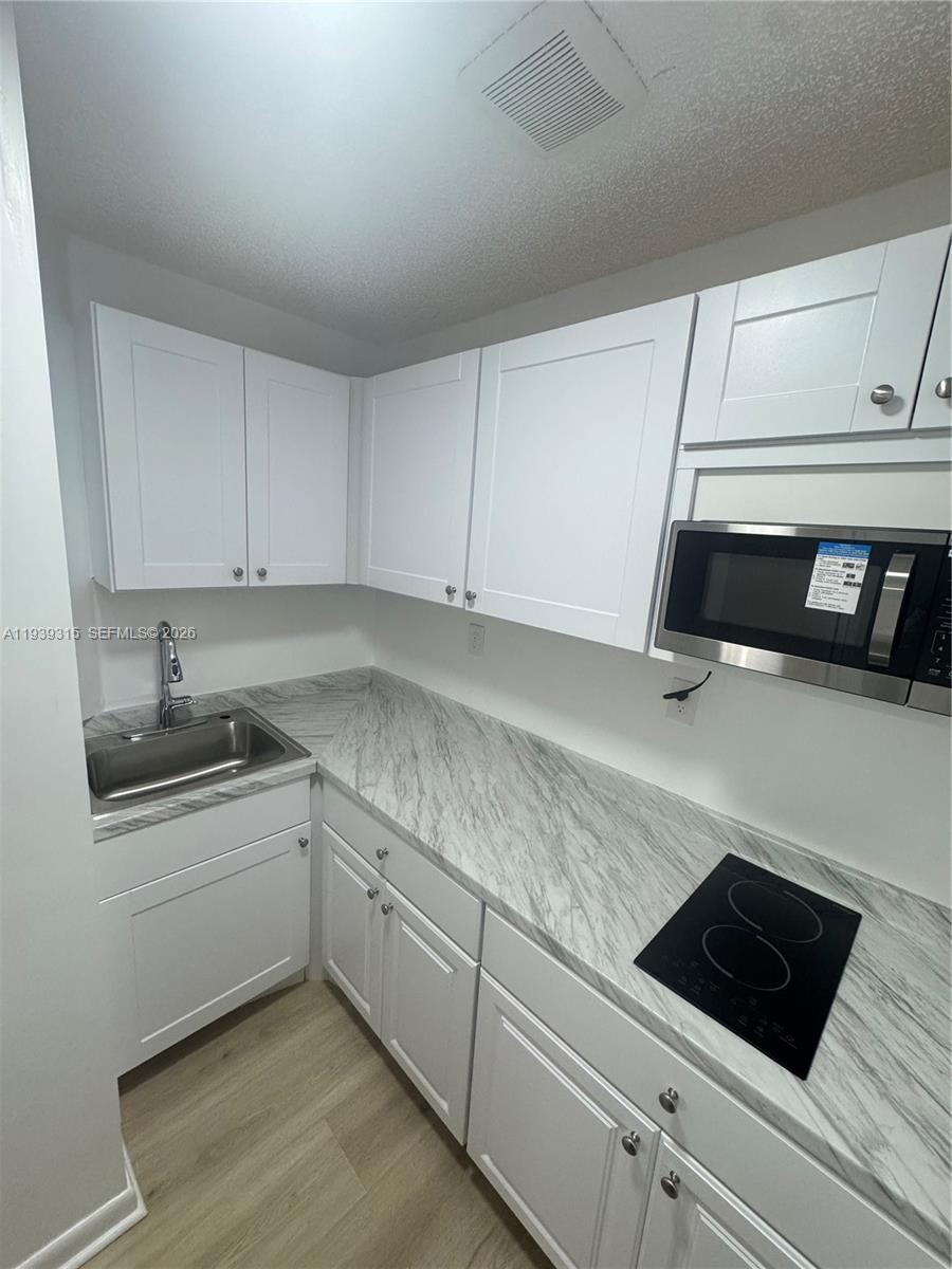 a kitchen with granite countertop white cabinets and white appliances