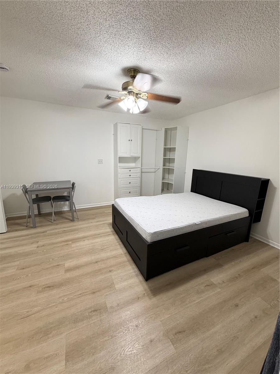 12828 Southwest 267th Street, Unit 1 Homestead, FL 33032 - Photo 4 of 7 a spacious bedroom with a bed and a chandelier