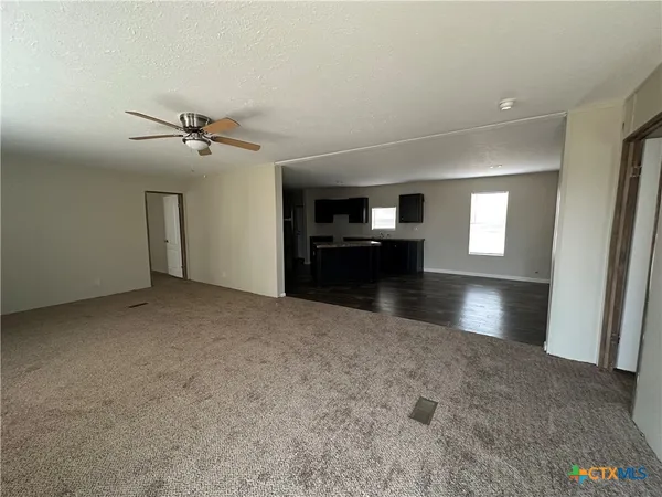 a view of an empty room and a kitchen