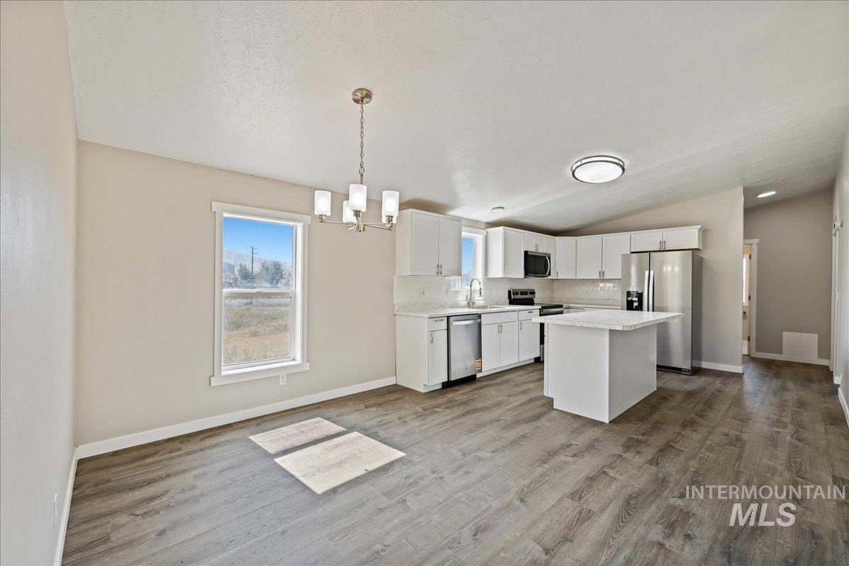 840 Highway 95 Weiser, ID 83672 - Photo 11 of 33 Kitchen with a center island, appliances with stainless steel finishes, tasteful backsplash, white cabinets, and pendant lighting