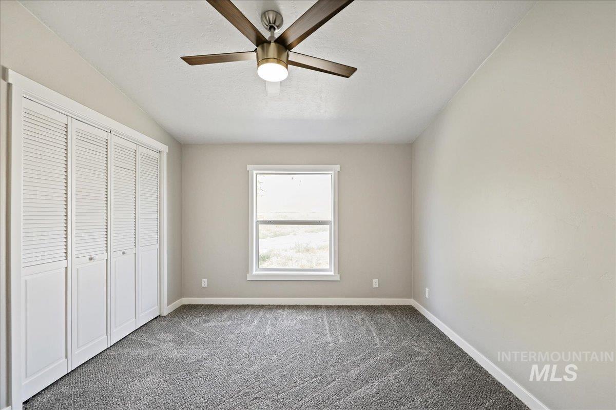 840 Highway 95 Weiser, ID 83672 - Photo 22 of 33 Unfurnished bedroom featuring dark colored carpet, a closet, ceiling fan, and a textured ceiling