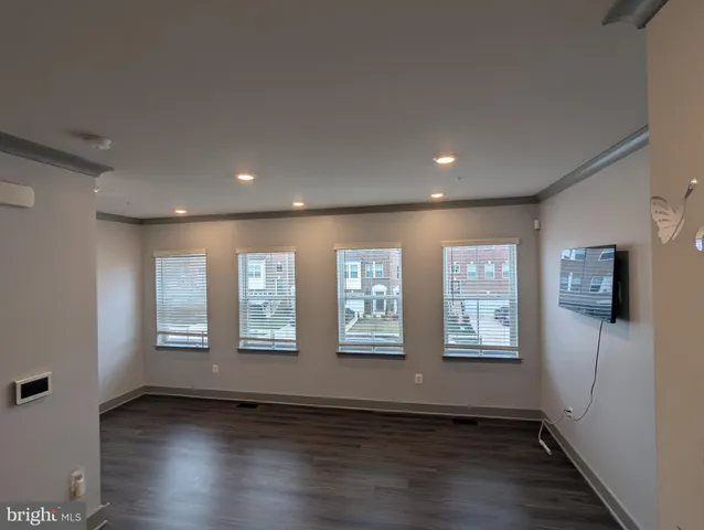 a view of an empty room with wooden floor and windows