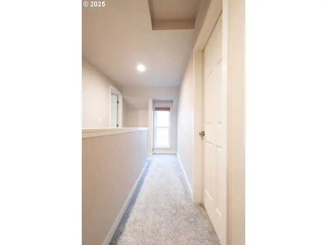 a view of a hallway with white walls plants and kitchen