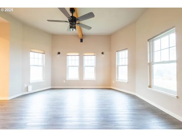 a view of an empty room with a window and wooden floor