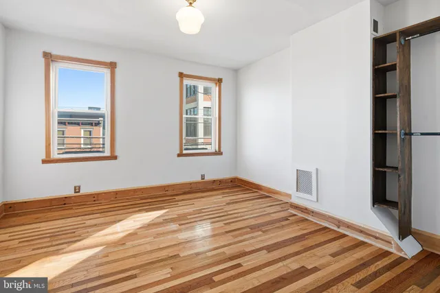 a view of empty room with wooden floor and fan