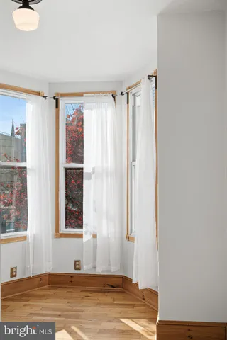 a view of an empty room with window and hardwood floor