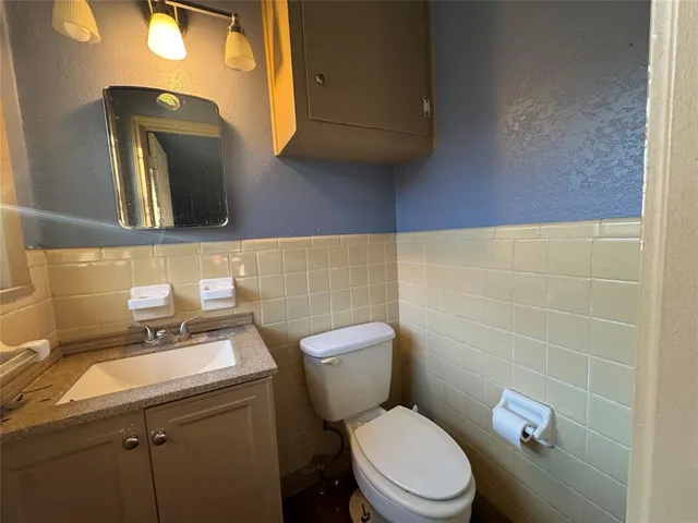 a bathroom with a granite countertop toilet sink and mirror