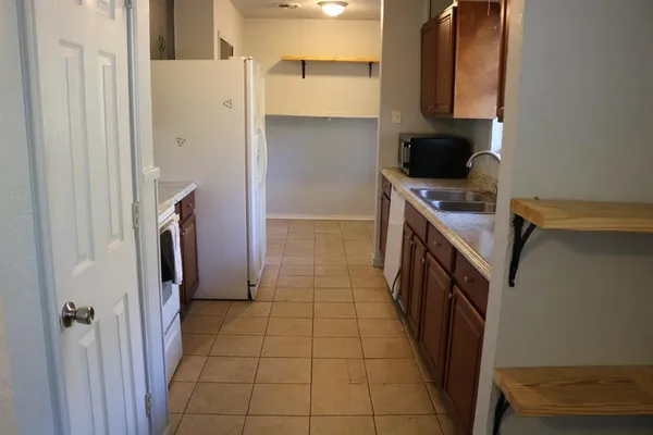 a kitchen with a sink a stove top oven a refrigerator and cabinets