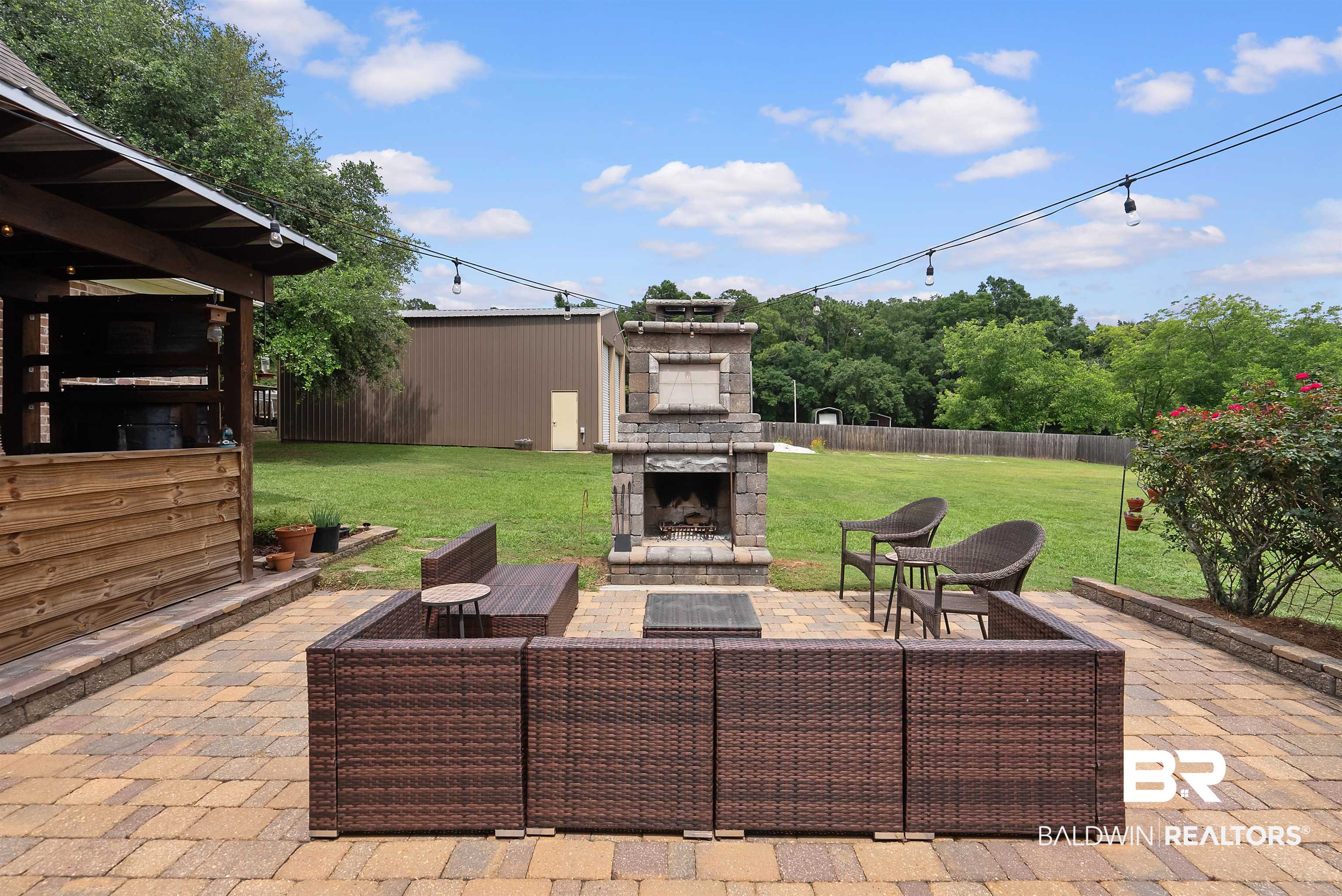 12070 Comalander Road Fairhope, AL 36532 - Photo 40 of 50 Expansive paver patio featuring a stone fireplace and an integrated fire pit