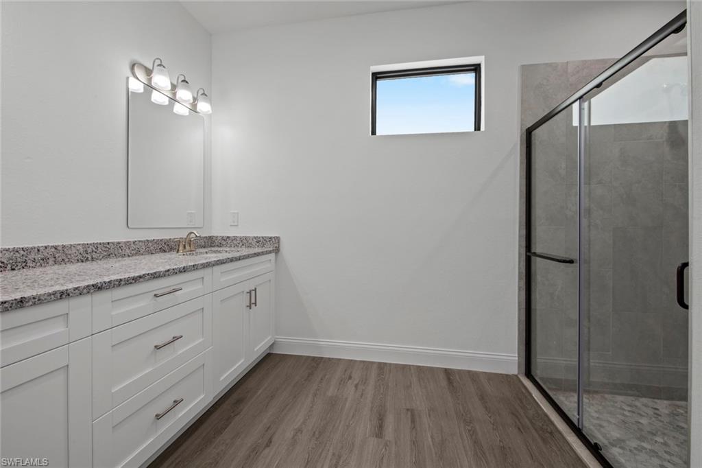 369 Ranier Avenue Lehigh Acres, FL 33974 - Photo 13 of 22 a bathroom with a granite countertop sink a mirror and shower